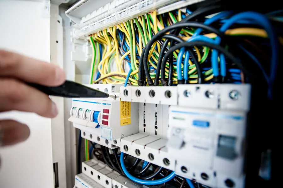 Técnico trabajando con herramienta en un cuadro con cableado